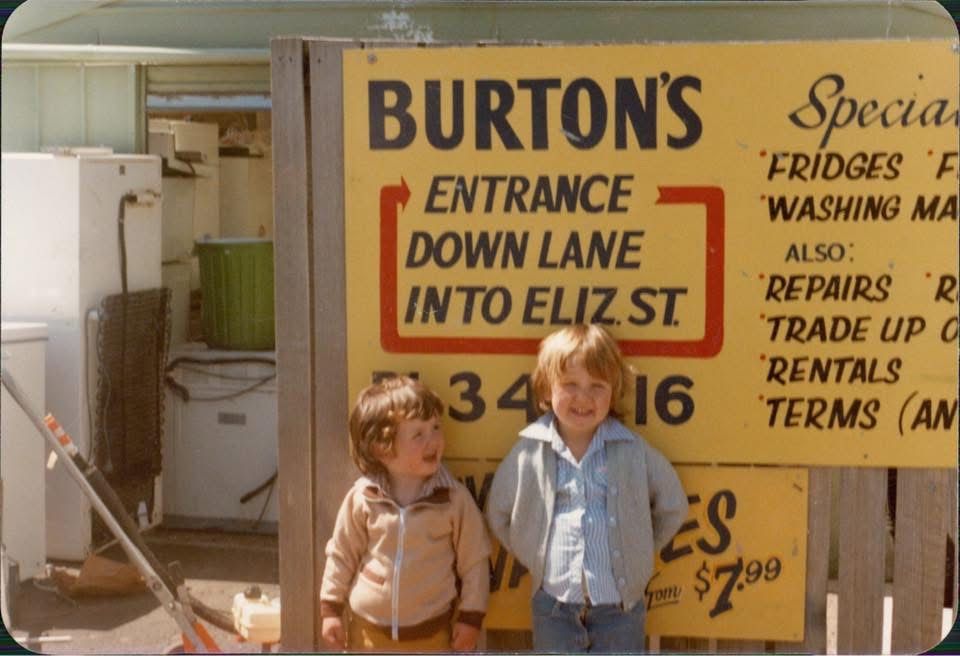Two young children in front of the yellow Burton's sign in North Hobart